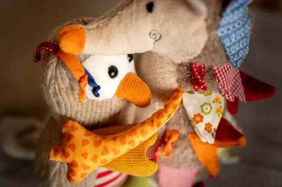 Plush hedgehog and owl hugging each other